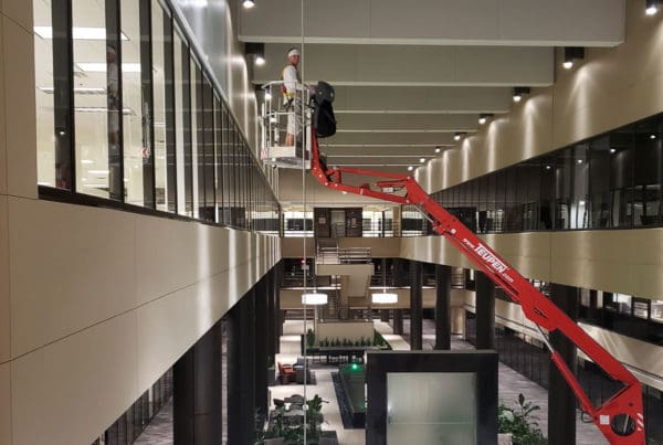 A professional painter using a lift to work on high ceilings in a commercial building.