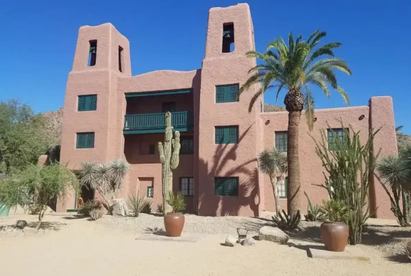 A building with a fresh coat of paint, surrounded by palm trees and lush plants.