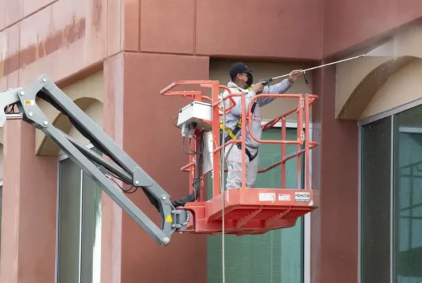 Painter using a paint sprayer to evenly coat a wall in fresh white paint, with focused concentration on achieving smooth coverage.